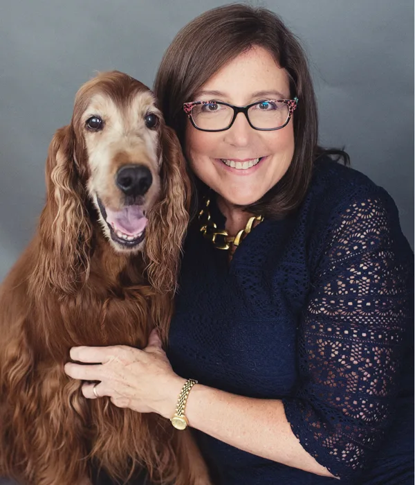Debra Vey Voda-Hamilton with Her Dog - Debra Hamilto Debra Vey Voda-Hamilton smiles warmly while posing with her long-haired dog, both looking at the camera. - Debra Hamilton